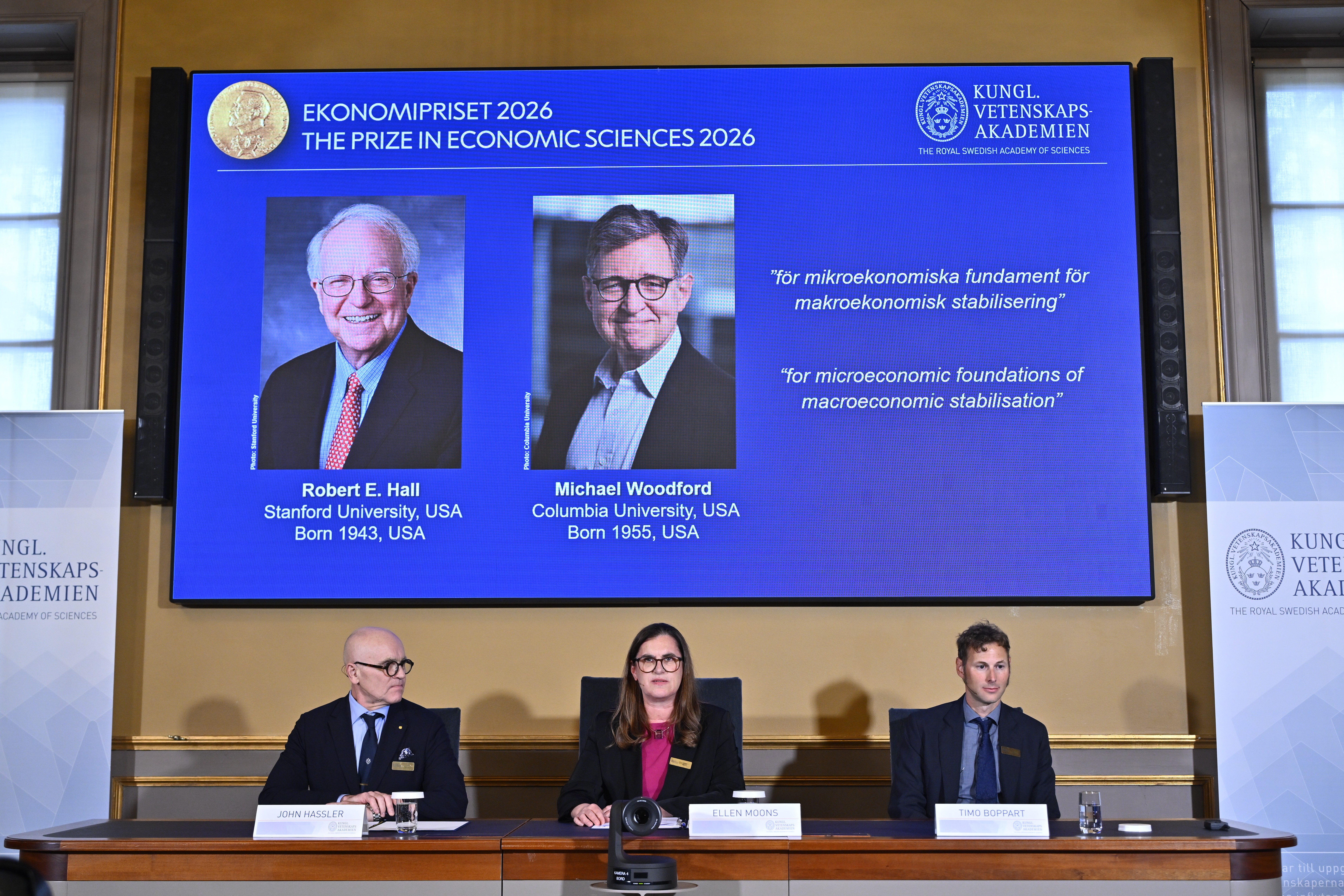 Portraits of Robert E. Hall and Michael Woodford are shown on the screen as they are announced as the laureates of the Sveriges Riksbank Prize in Economic Sciences in Memory of Alfred Nobel at the Royal Swedish Academy of Sciences in Stockholm, Sweden, Monday, Oct. 12, 2026. 