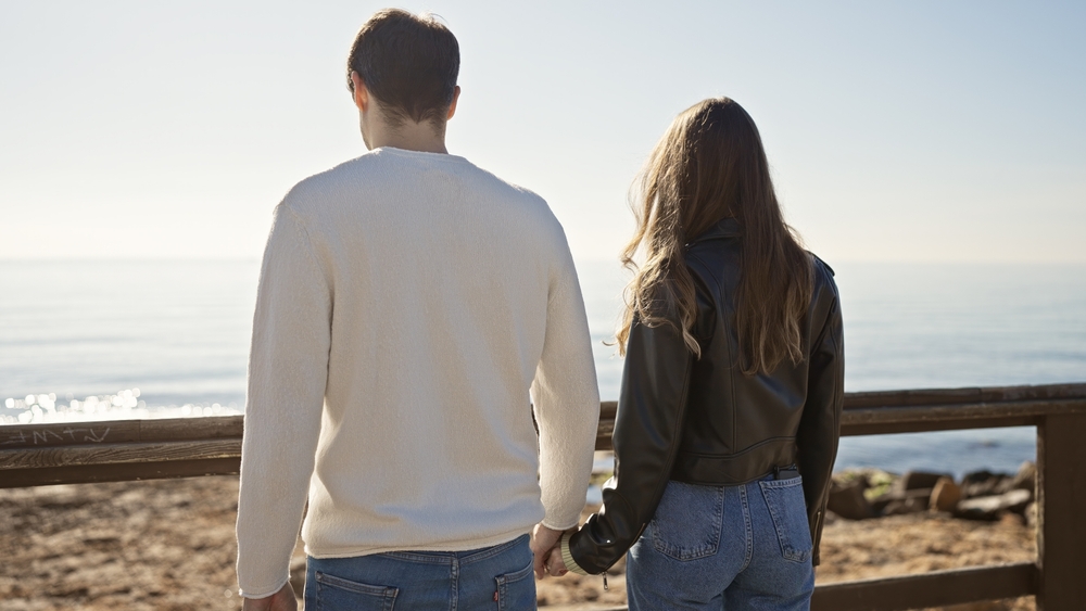 Stock image of a man and woman holding hands on a boardwalk.