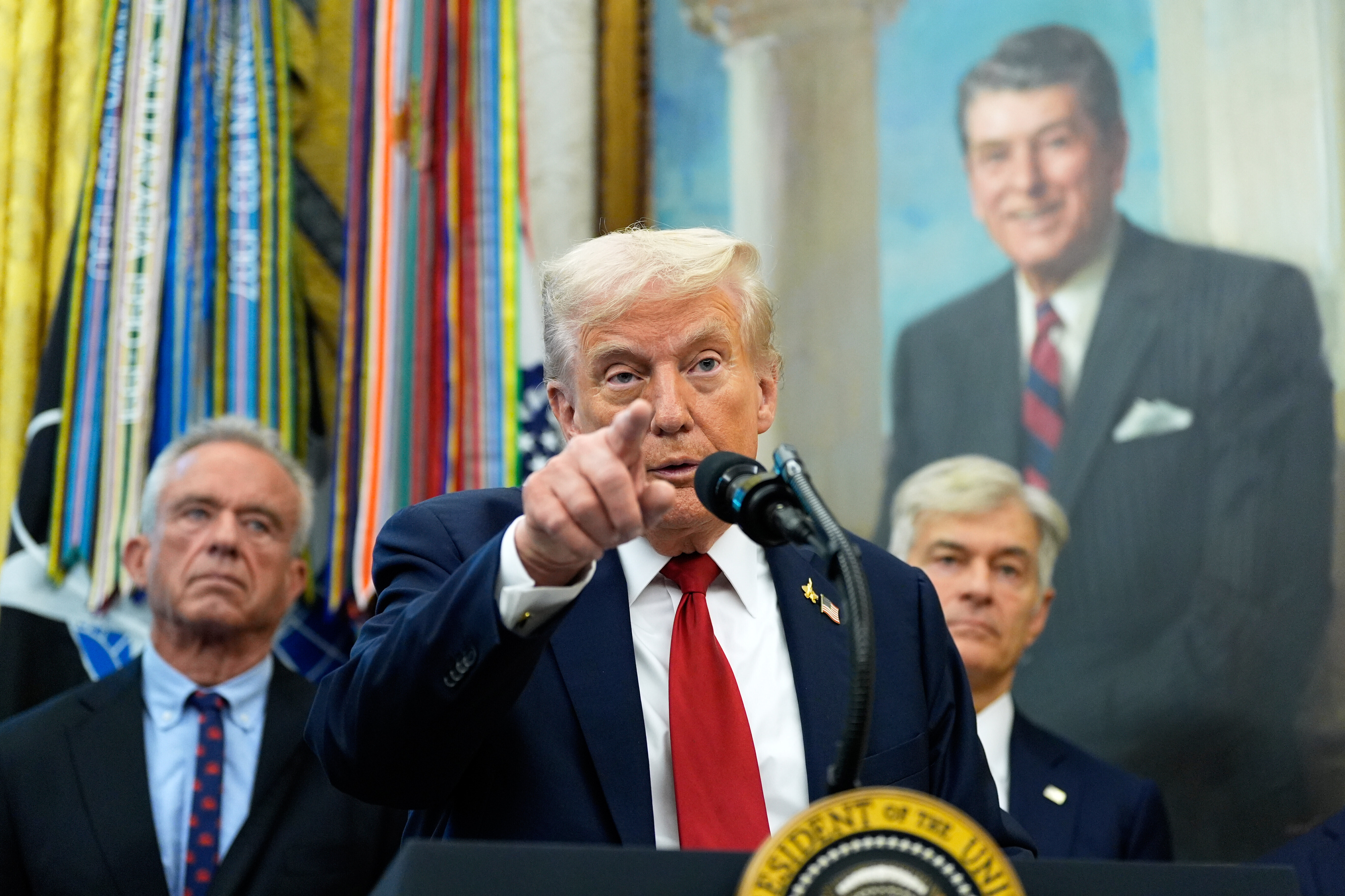 President Donald Trump speaks in the Oval Office of the White House, Tuesday, Sept. 30, 2025, in Washington, as Secretary of Health and Human Services Robert F. Kennedy, Jr., left, and Mehmet Oz, Administrator for the Centers for Medicare & Medicaid Services, look on. 