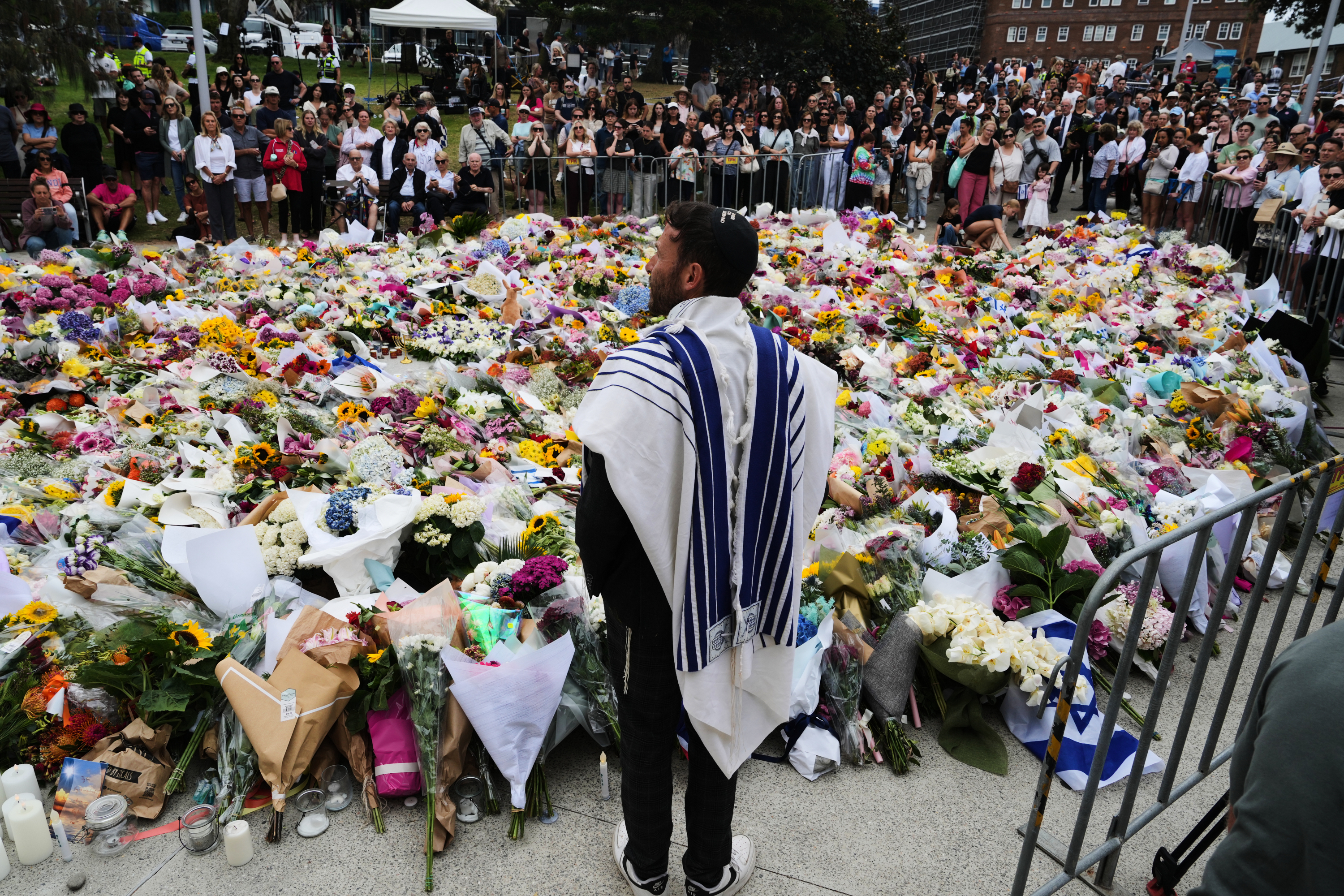 Rabbi Yossi Friedman speaks to people gathering at a flower memorial by the Bondi Pavilion at Bondi Beach on Tuesday, Dec. 16, 2025, following Sunday's shooting in Sydney, Australia.