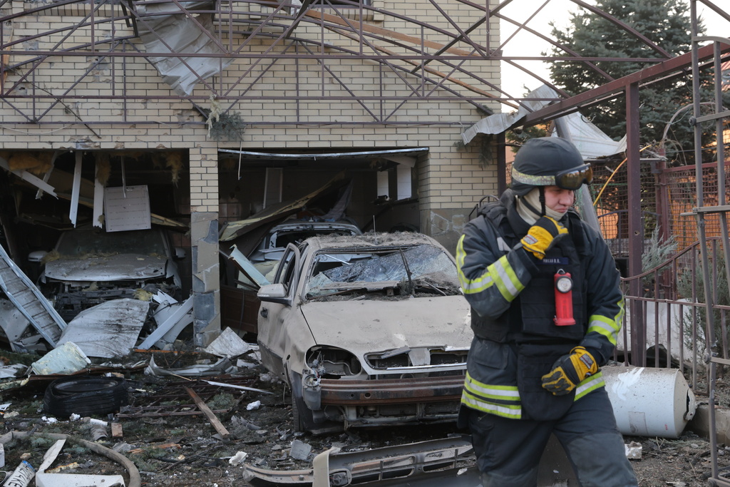 A rescue worker walks in front of a residential house damaged after a Russian attack on Zaporizhzhia, Ukraine, Friday, Dec. 19, 2025. 