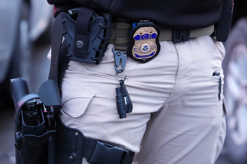 The badge and gun of an ICE officer is seen as a person is detained, Saturday, Jan. 10, 2026, in Richfield, Minn.