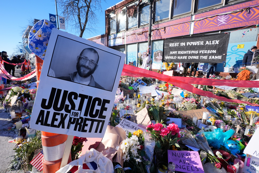People gather around a memorial site for Alex Pretti on Saturday, Jan. 31, 2026, in Minneapolis. 