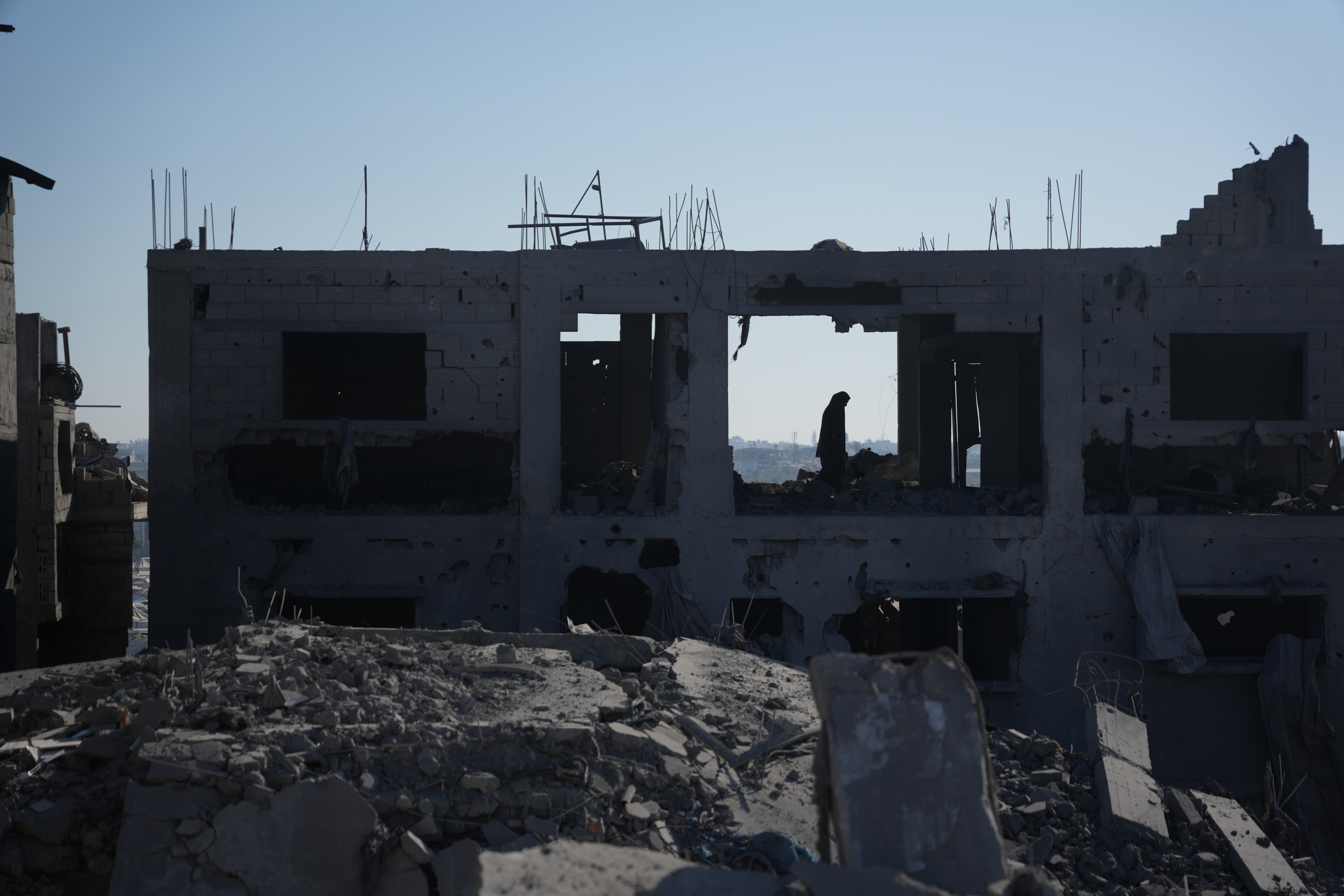 A Palestinian woman inspects a destroyed building following an Israeli airstrike in Deir al-Balah, central Gaza Strip, Sunday, July 19, 2026.