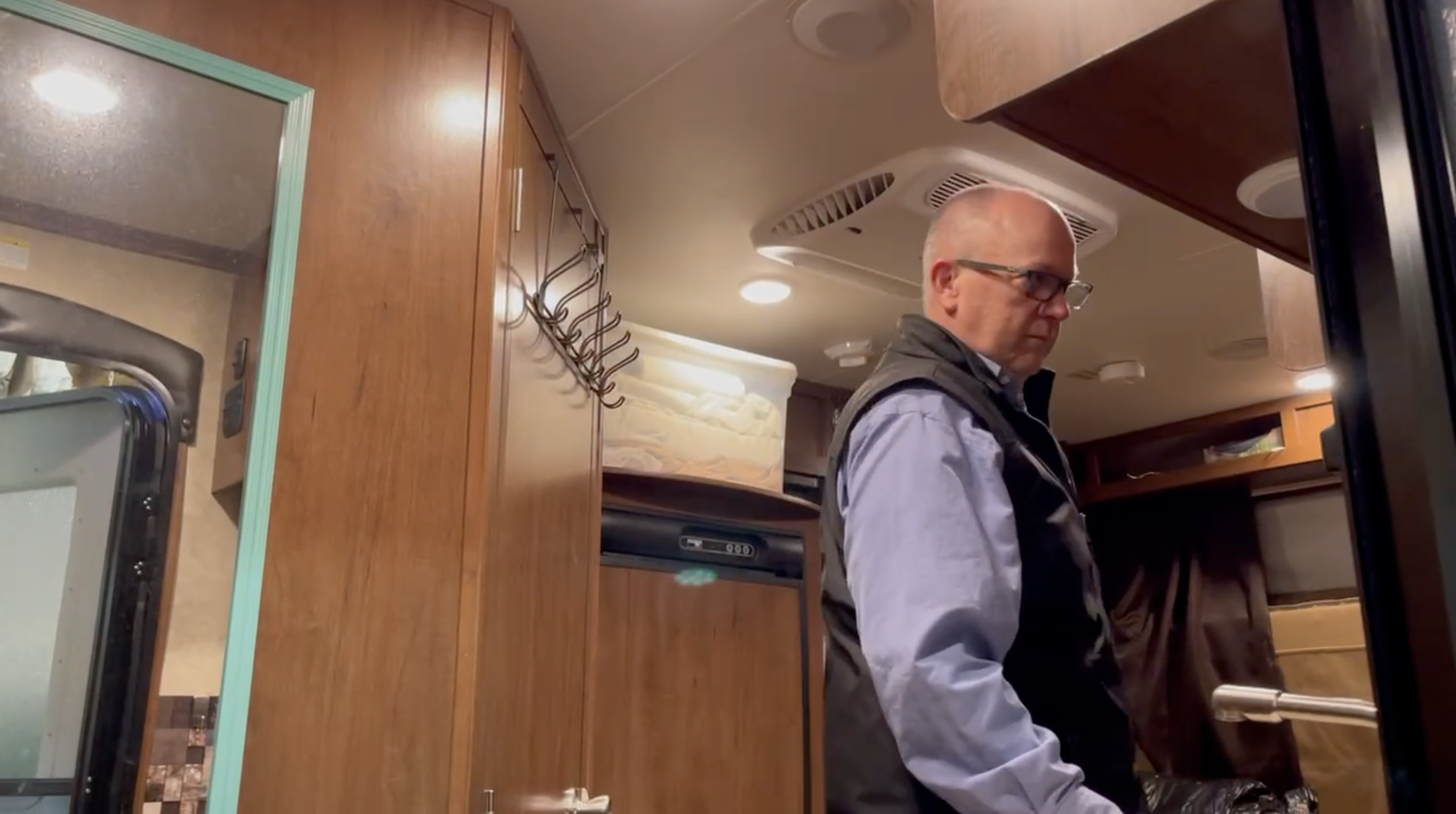 Mike Brady is walking around his camper. 