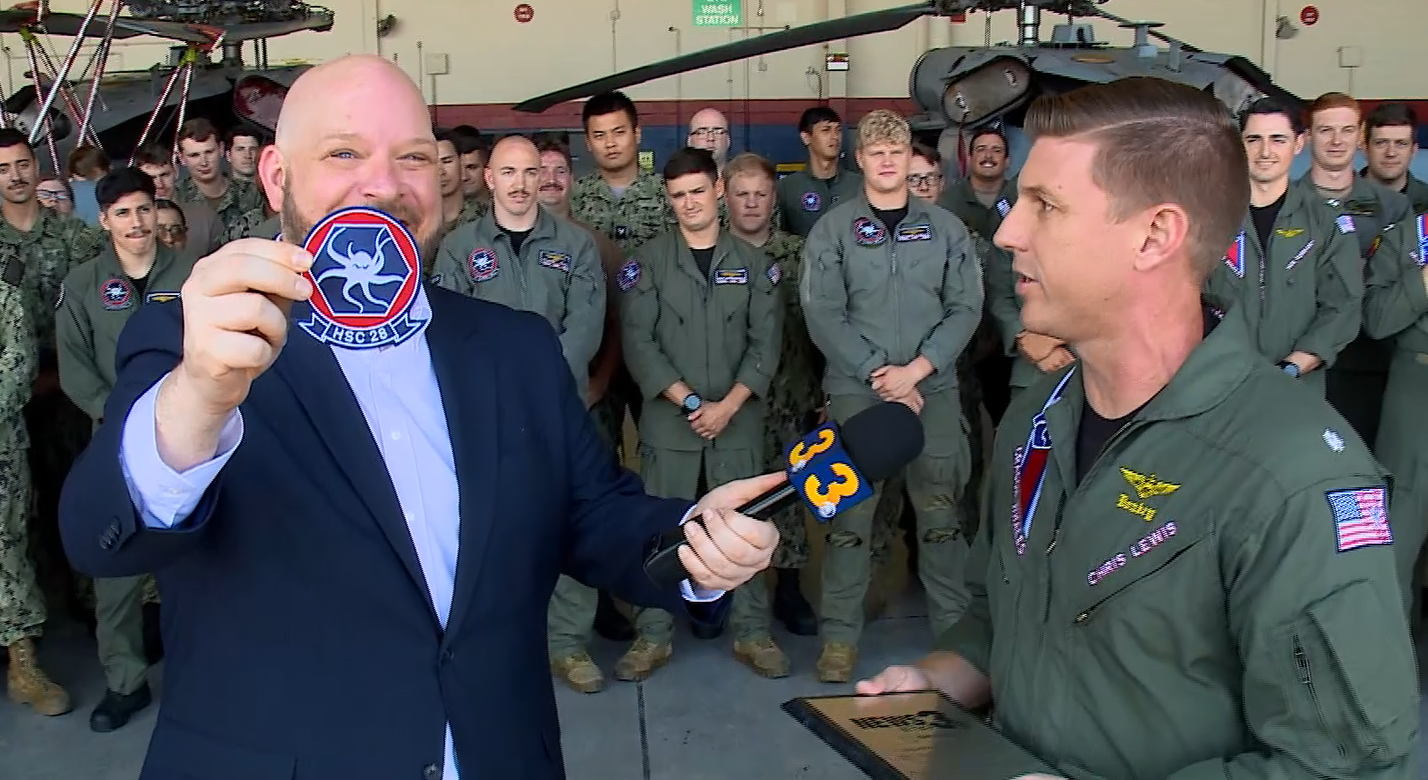 Cmdr Christopher Lewis presents News 3 anchor Blaine Stewart with an HSC-28 patch.png