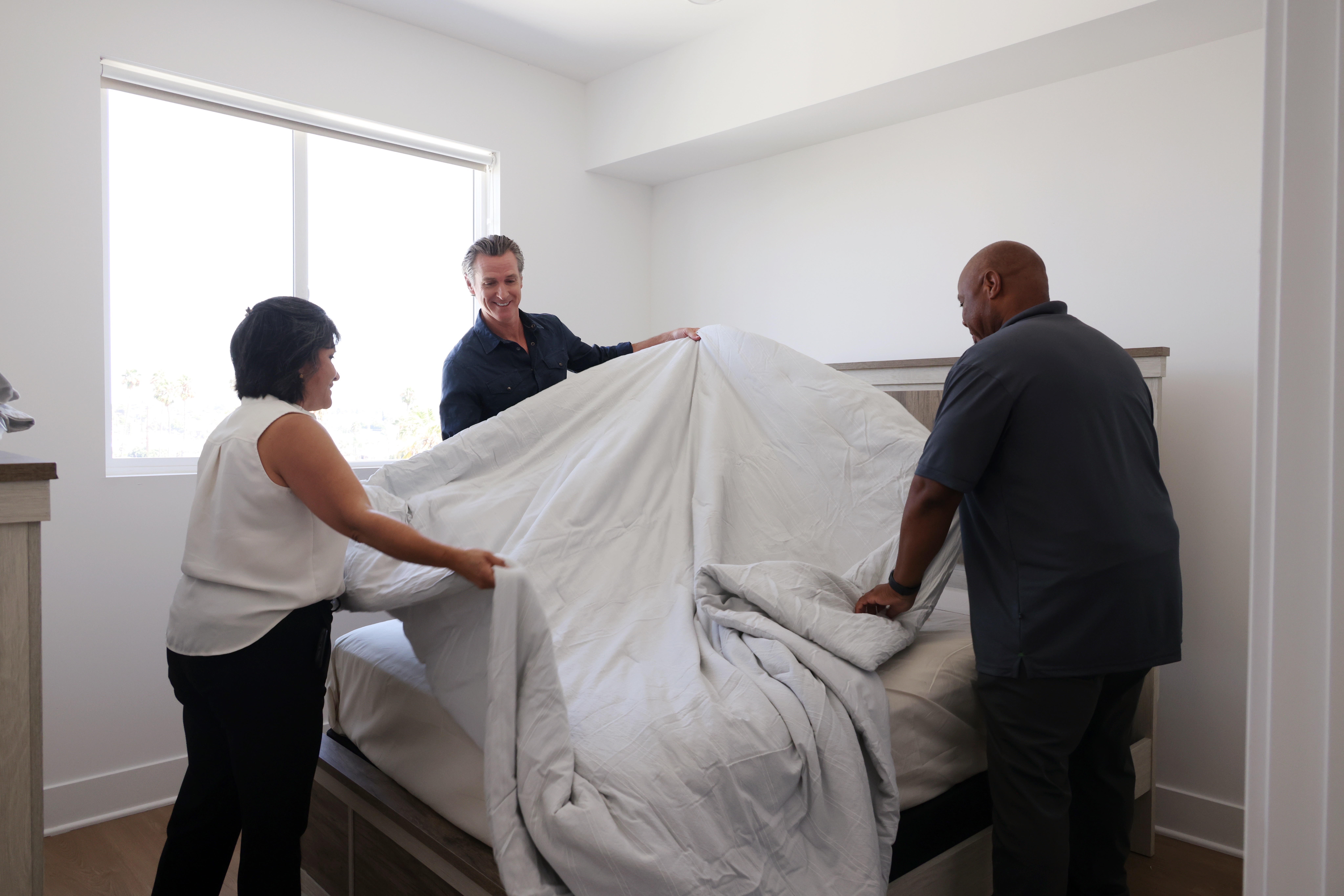 Gavin Newsom helps volunteers make a bed.