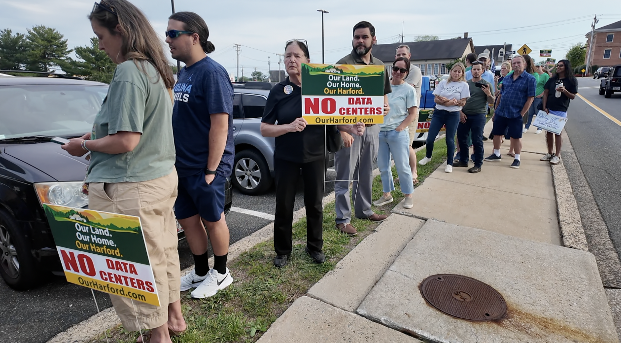 Neighbors lining up outside council chambers with 'no data centers' signs