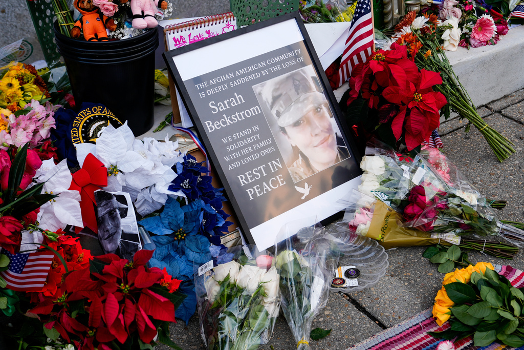 Flowers, challenge coins and other items lay near a photograph of U.S. Army Spc. Sarah Beckstrom at a makeshift memorial outside of Farragut West Station, near the site where two National Guard members were shot in Washington, D.C.