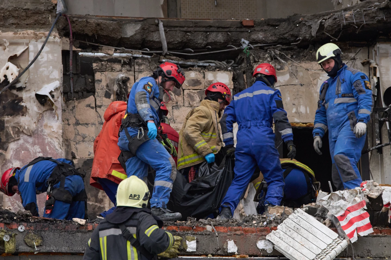 Rescuers carry the body of a victim after a Russian drone strike hit a multi-story apartment building during a massive missile and drone attack in Kyiv, Ukraine, Saturday, Dec. 27, 2025.