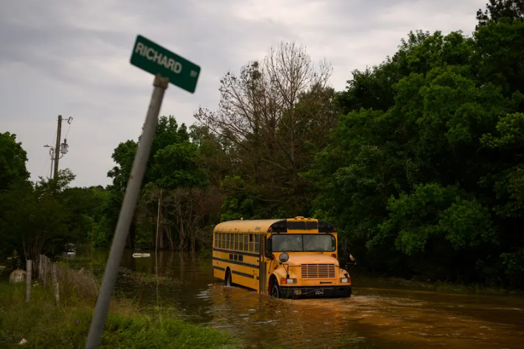 A school bus drives through floodwater to survey the damage as peoples’ homes and possessions are submerged in floodwater following significant rainstorms in Coldspring May 4.