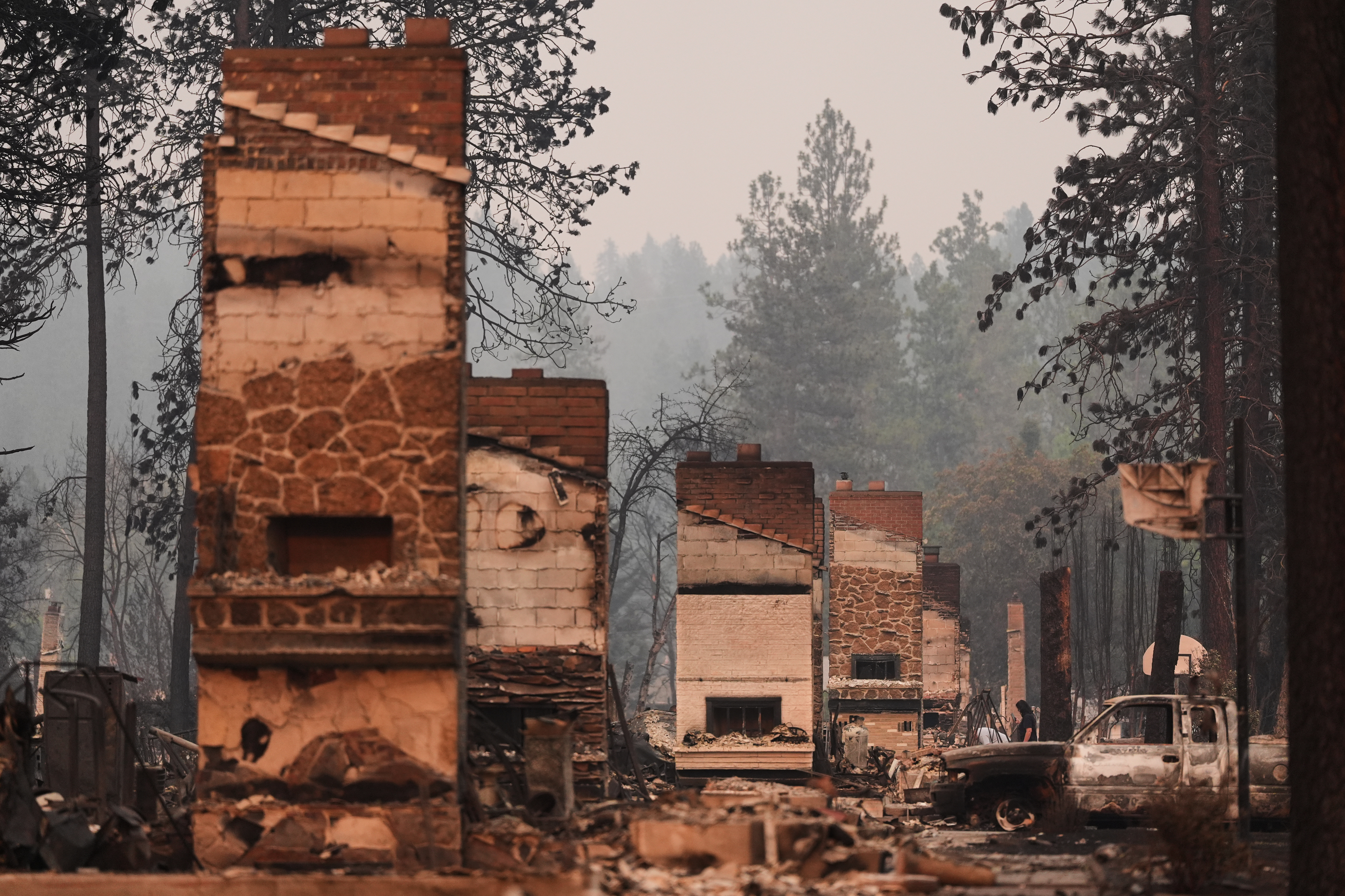 Chimneys are the only structures remaining in a residential neighborhood after a wildfire hit the northern part of Spokane, Wash., Monday, Aug. 3, 2026.