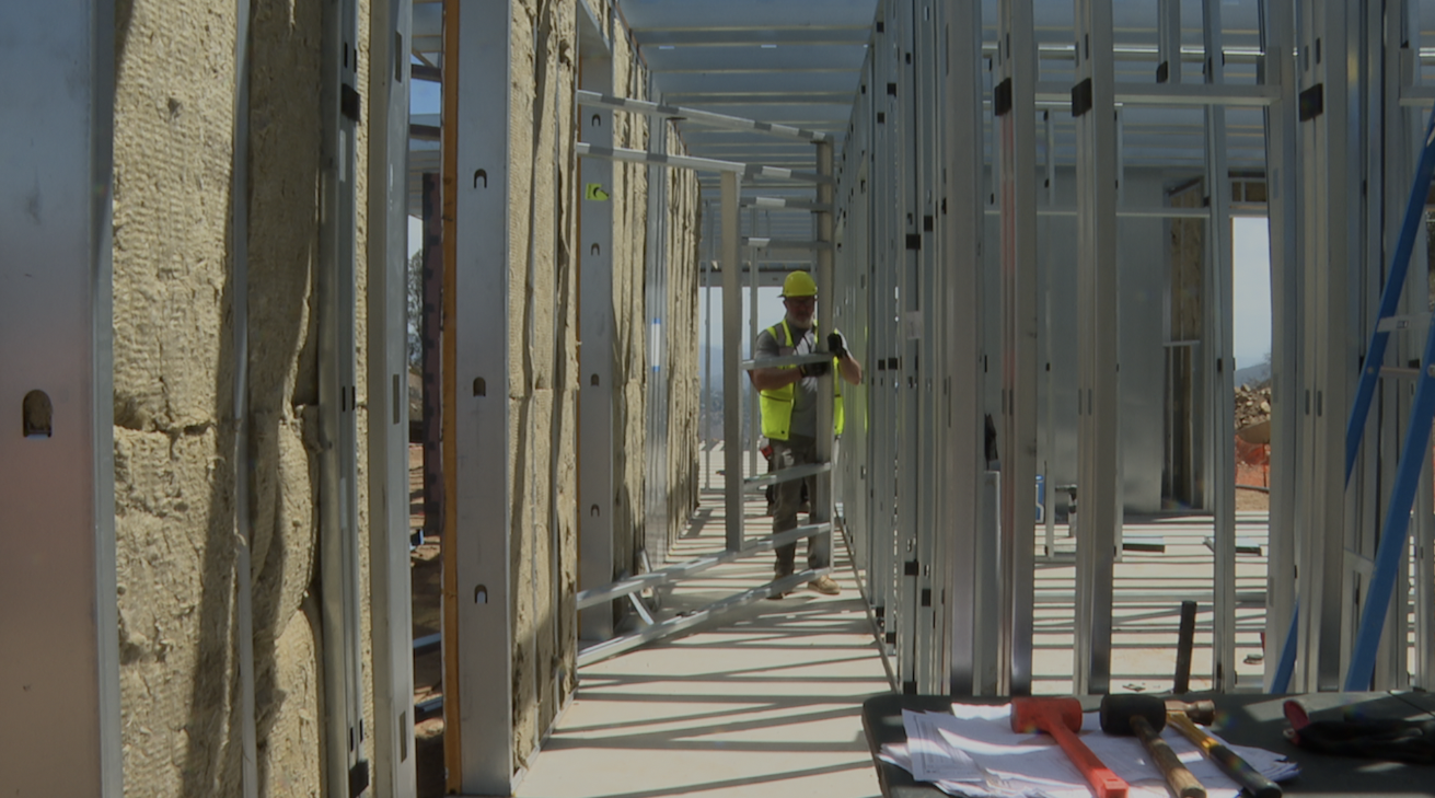 Construction workers helping build the shell of a fire-resistant home. 