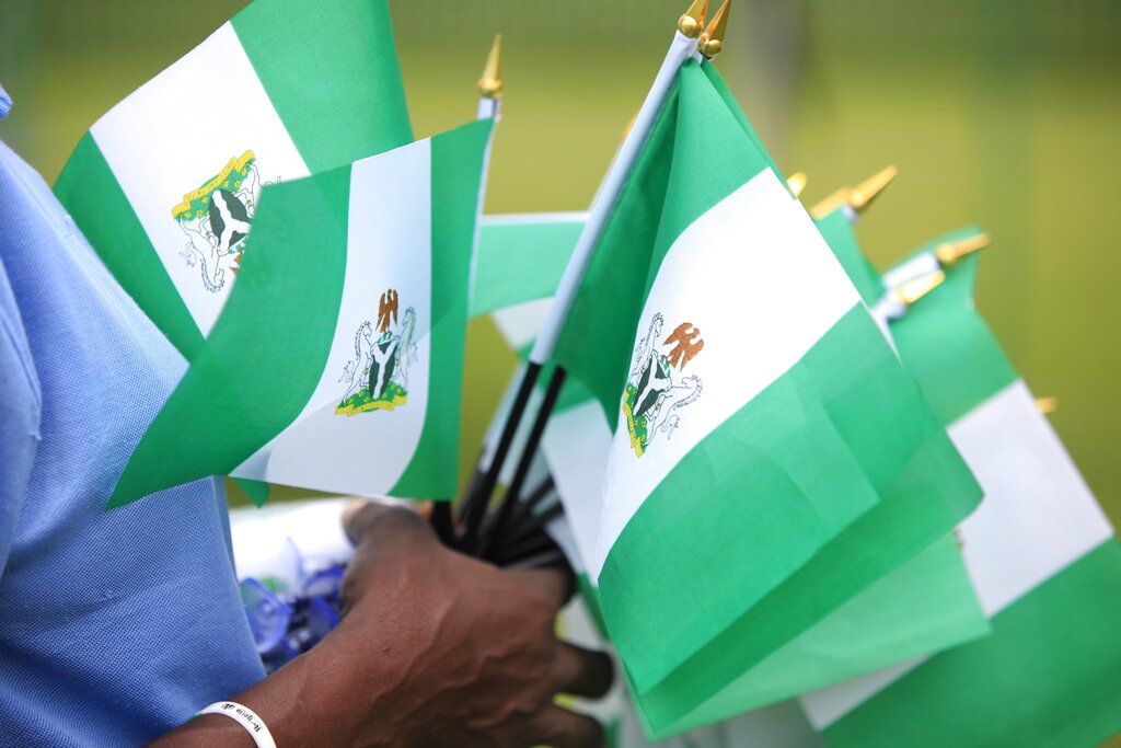 A person holding Nigerian national flags.