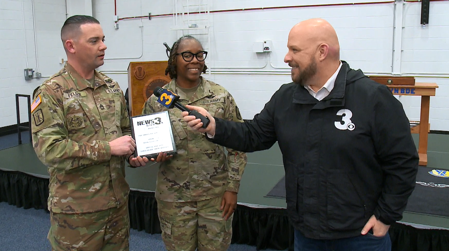 1News 3 anchor Blaine Stewart presents the Squadron of the Month award to members of the Army's 128th Aviation Brigade at Fort Eustis.