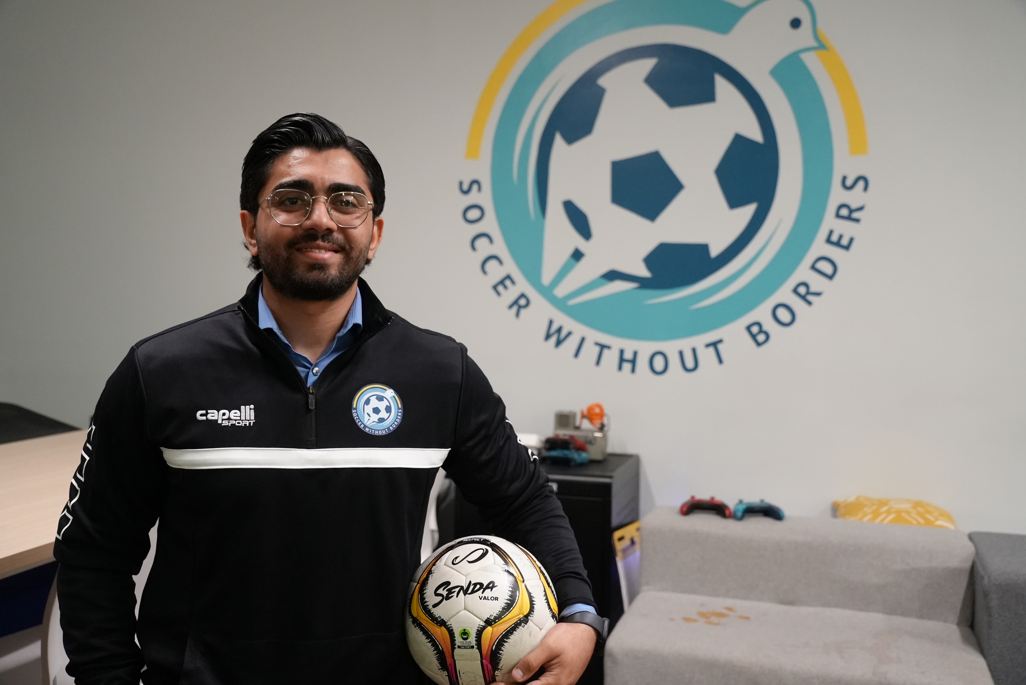 Warshan Hussin in front of the Soccer Without Borders logo