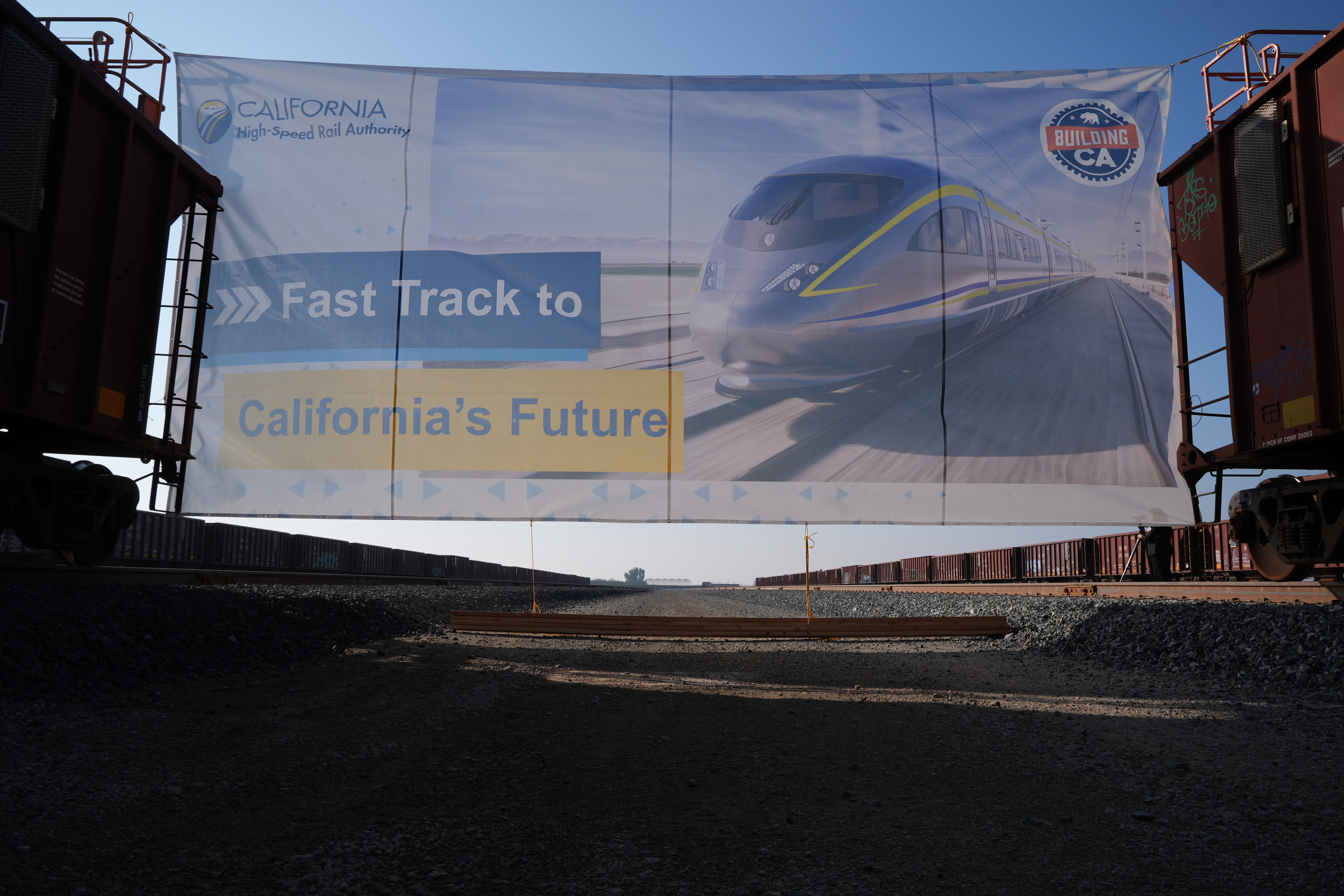 A banner reading "Fast Track to California's Future" is displayed at the California High-Speed Rail Authority's 150-acre Southern Railhead site in the Wasco/Shafter area for the announcement of the next phase of construction, bringing the state closer to passenger service by starting track installation between Merced and Bakersfield, in Wasco, Calif., Tuesday, Feb. 3, 2026.