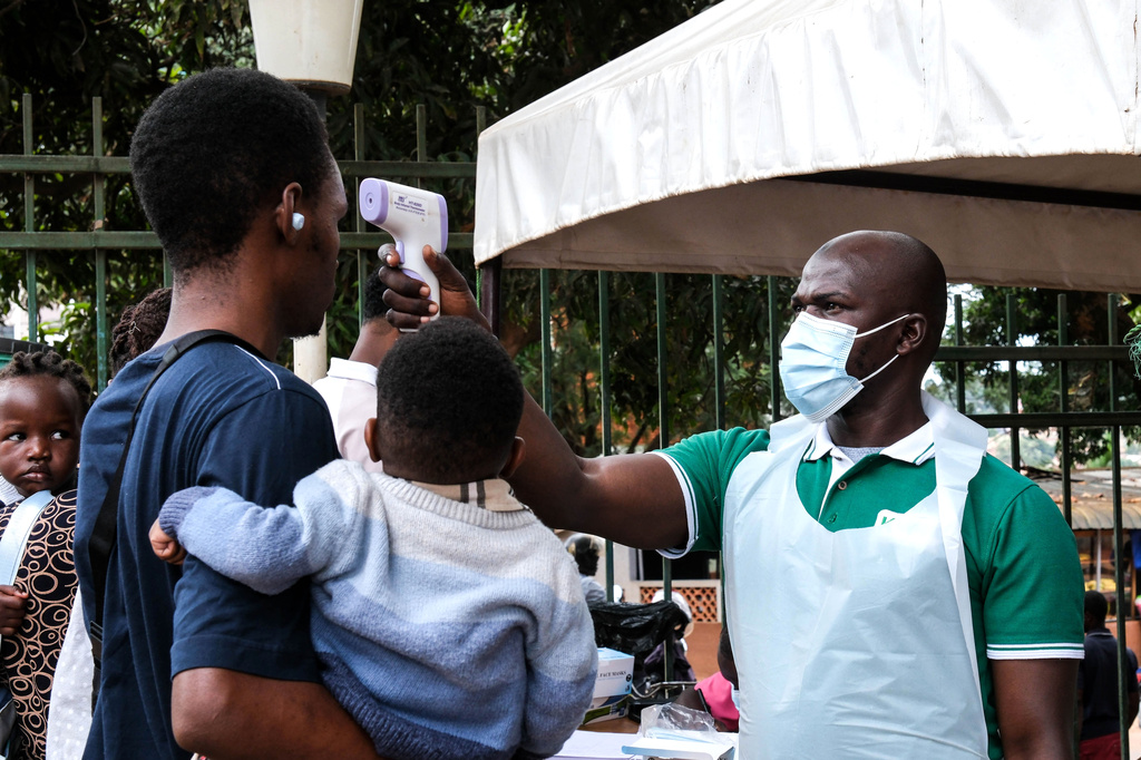 A health official uses a thermometer to screen people in front of Kibuli Muslim Hospital in Kampala, Uganda, Saturday, May 16, 2026.