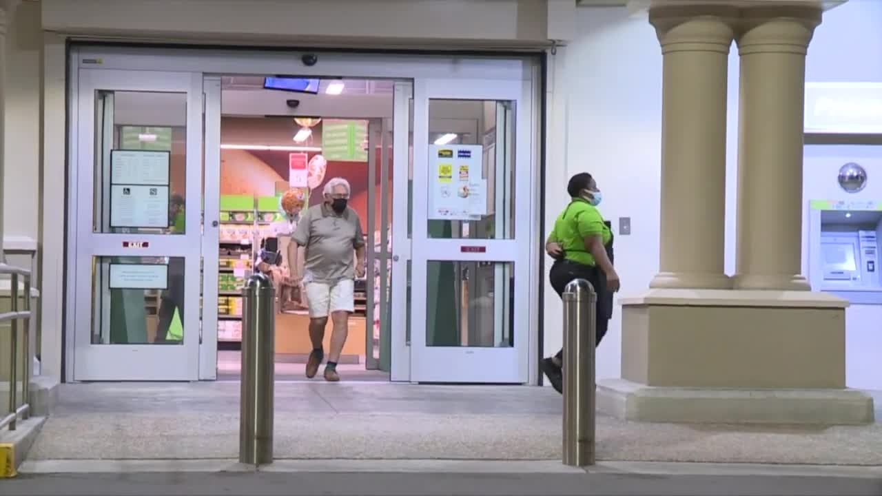 shopper and employee of Publix walk outside store on night wearing masks, May 14, 2021