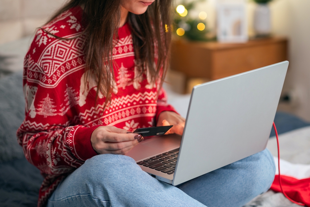 Stock image of a woman shopping for holiday gifts online.