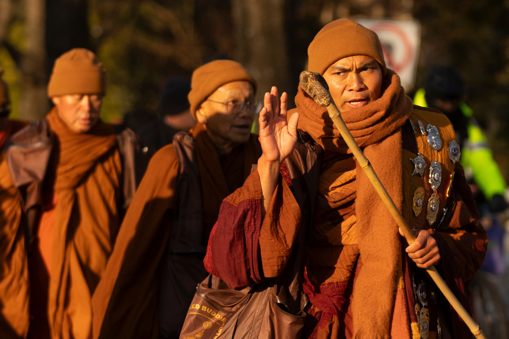 Monk Bhikkhu Pannakara waves as Buddhist monks who are participating in a Walk For Peace walk through a neighborhood on Tuesday, Feb. 10, 2026, in Washington.