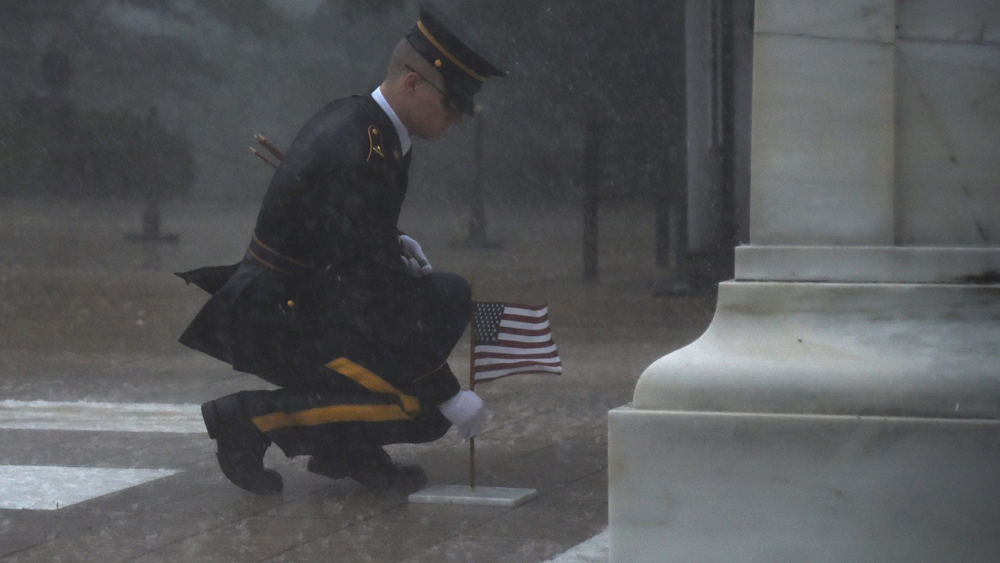 A soldier doesn't let a storm keep him from planting a flag Thursday at the Tomb of the Unknown Soldier.