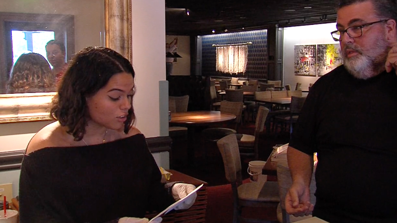 Restaurant owner Robert Ghini gives hostess Christina Sentmanat $500 as part of a $20,000 donation he received from a customer.