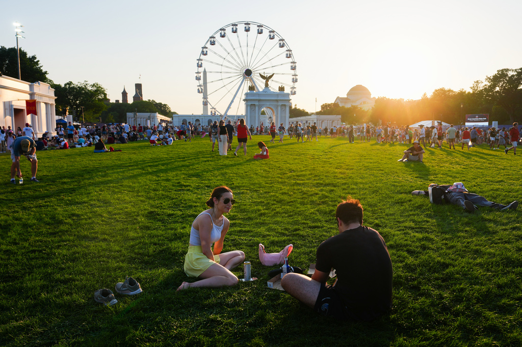 People sit on the National Mall at sunset during the Great American State Fair, in an extreme heat wave, Friday, July 3, 2026, in Washington. 