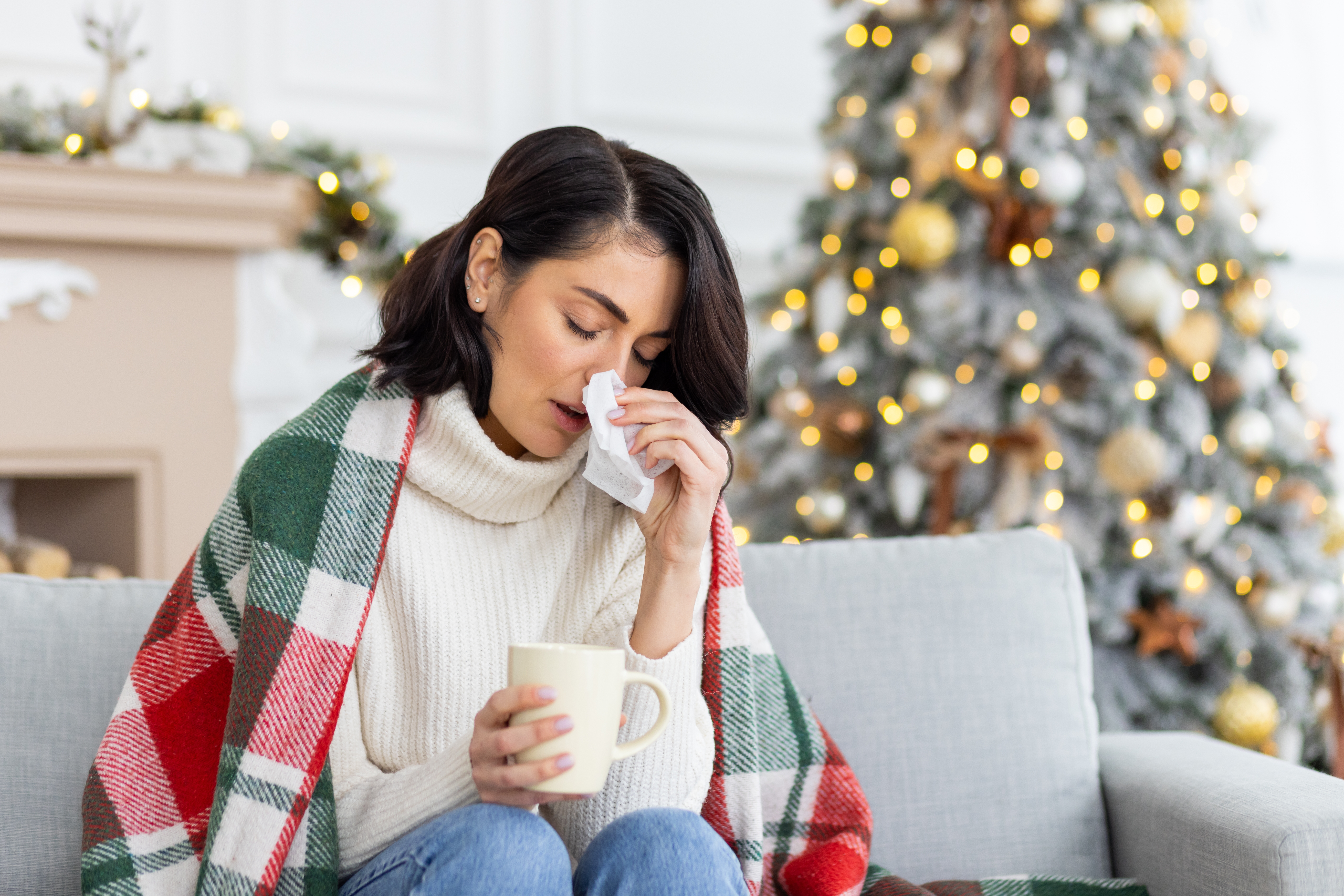 Stock image of a sick woman wiping her nose during the holidays.