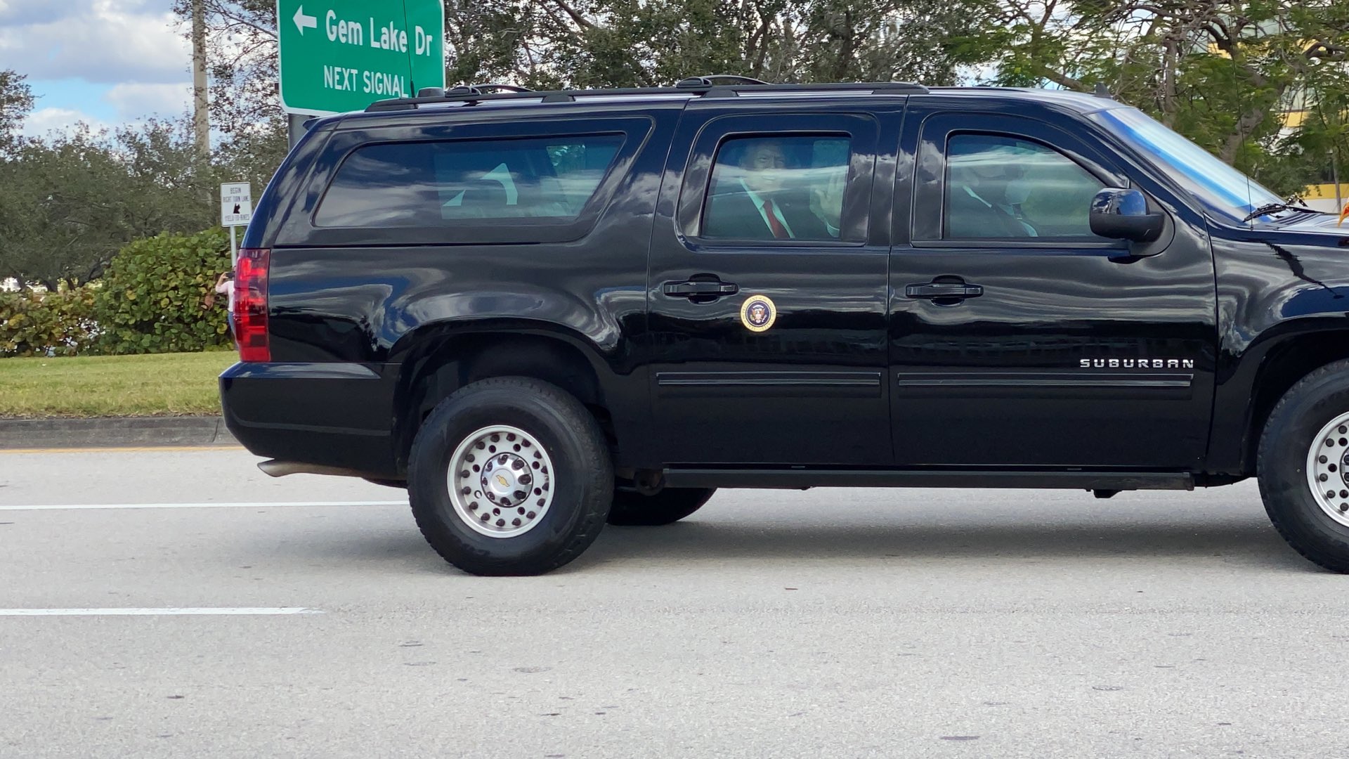President Donald Trump waves to supporters as motorcade passes through West Palm Beach
