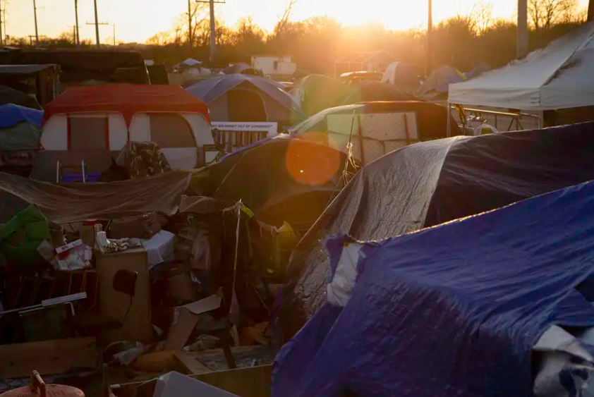 The sun sets over the tops of tents at a homeless encampment on state-owned land in Austin on Jan. 18, 2021.