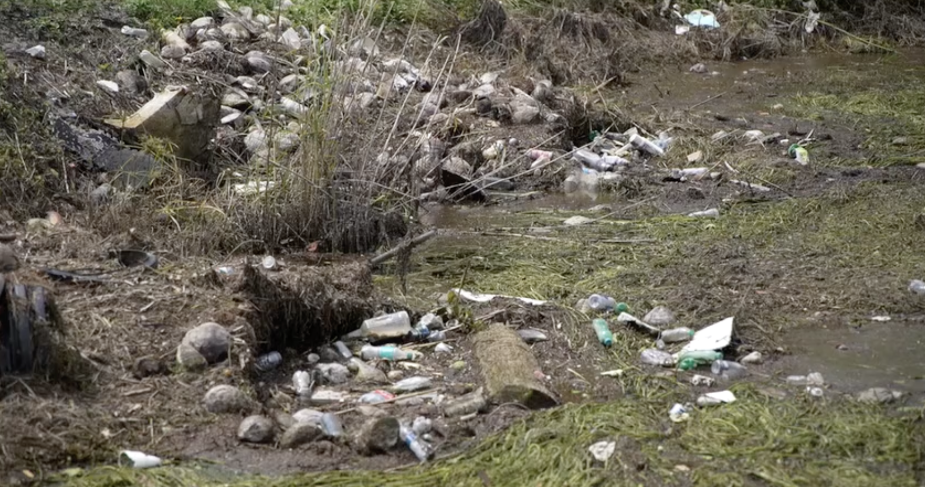 Garbage and debris clog a drainage canal in The Acreage, slowing efforts to lower floodwaters.