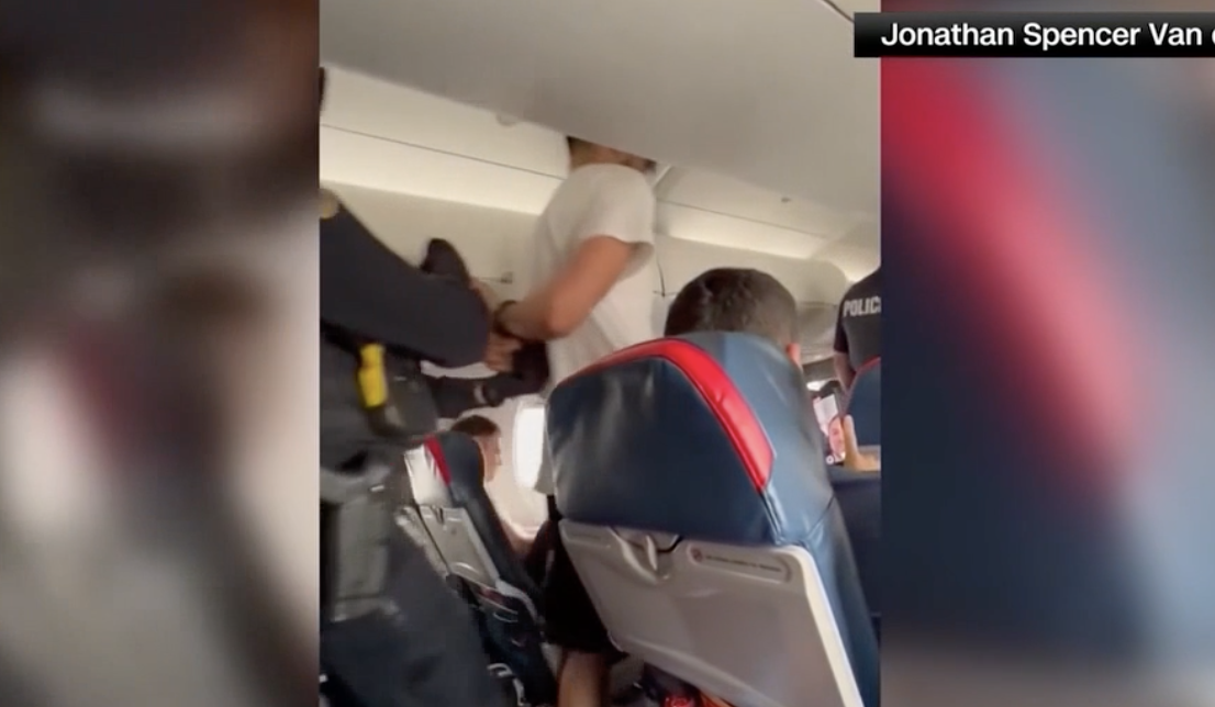Man in handcuffs led out of an airplane.