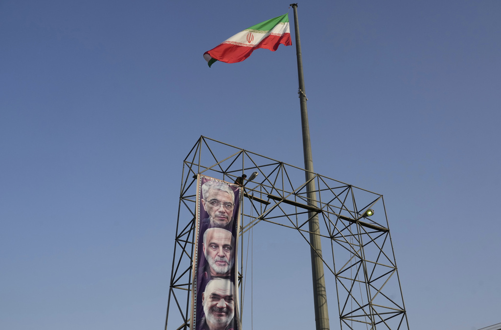 A worker hangs a banner showing portraits of the late Iranian armed forces commanders, Gen. Mohammad Hossein Bagheri, top, Gen. Gholamali Rashid, center, and Gen. Hossein Salami who were killed in Israeli strike in June at Baharestan Sq. in Tehran, Monday, Sept. 22, 2025. 