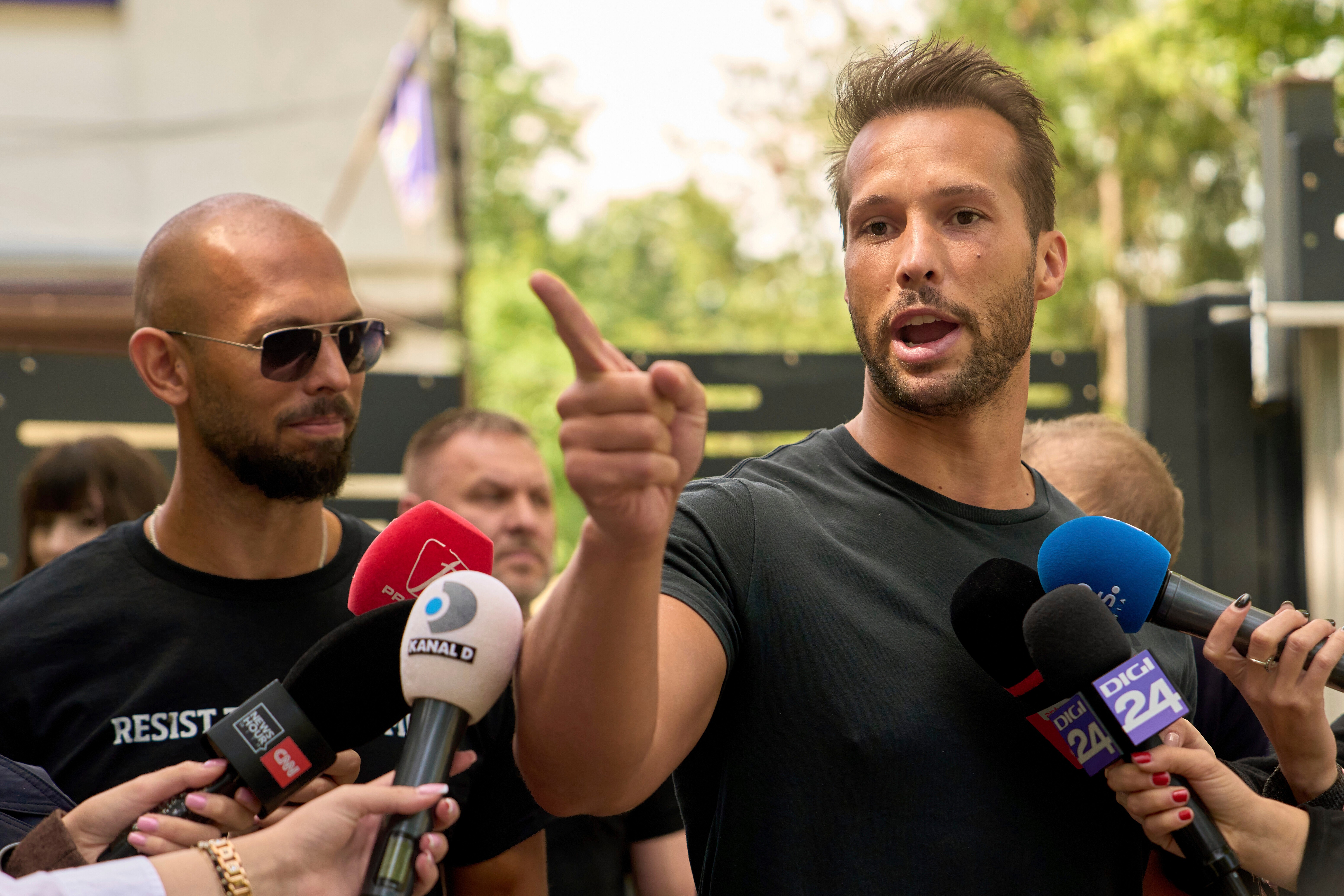 FILE - Andrew Tate, left, watches his brother Tristan speak, outside a police station in Voluntari, Romania, May 21, 2025.