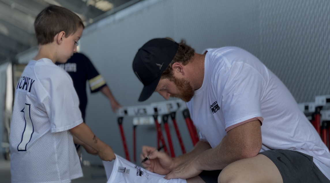 Seattle Seahawks' Will Dissly signs a shirt at his youth football camp.