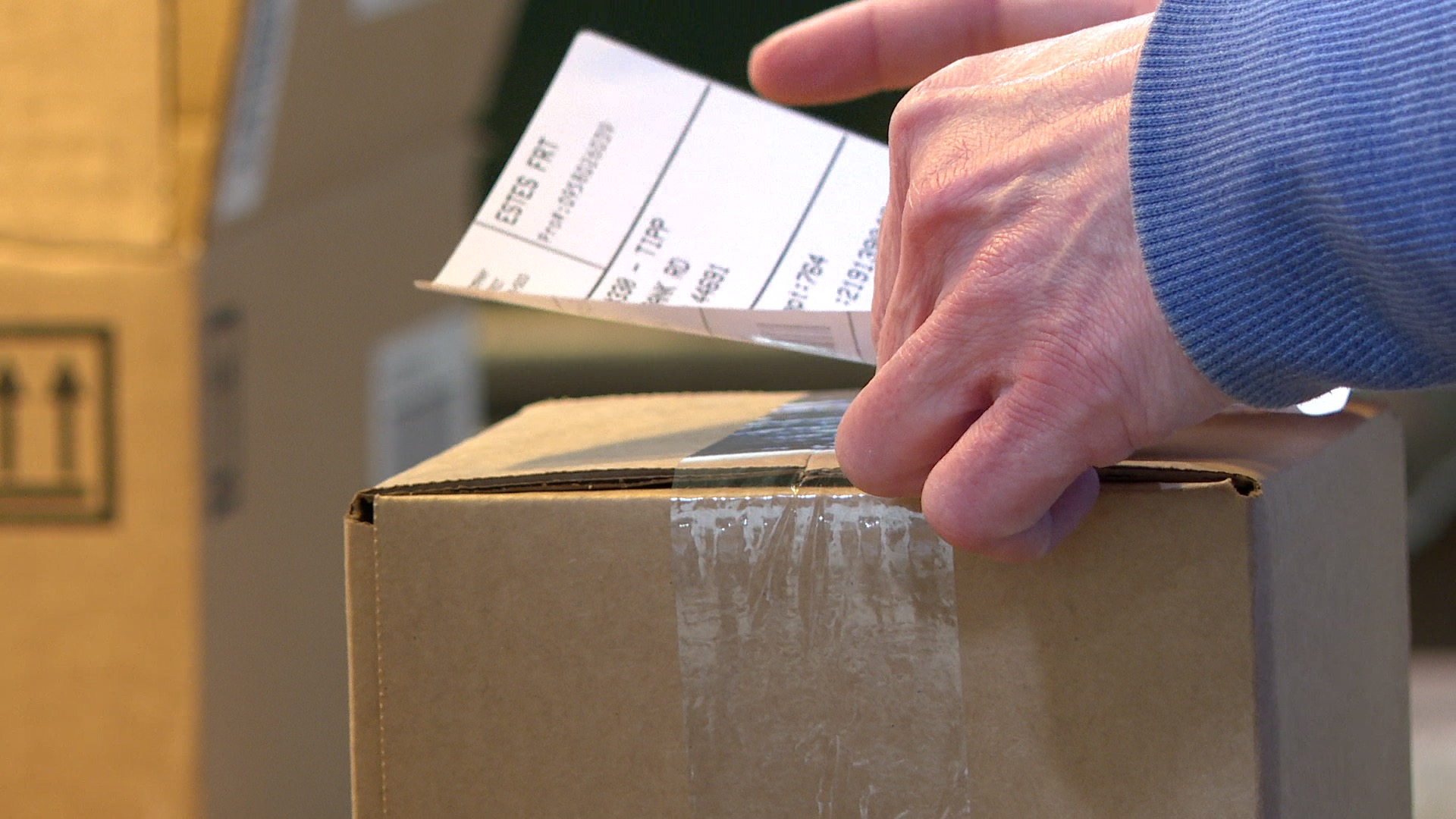 Worker at Silver Lead Company in Lansing places shipping label on package