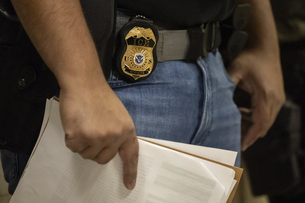 A federal agent wears a badge of Immigration and Customs Enforcement while standing outside an immigration courtroom at the Jacob K. Javits Federal Building in New York, Tuesday, June 10, 2025. 