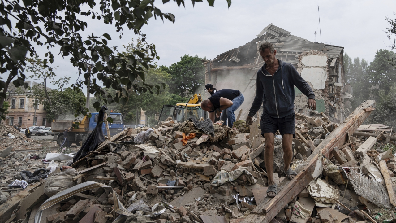 Residents search for documents of their injured friend in the debris of a destroyed apartment house in Ukraine after shelling