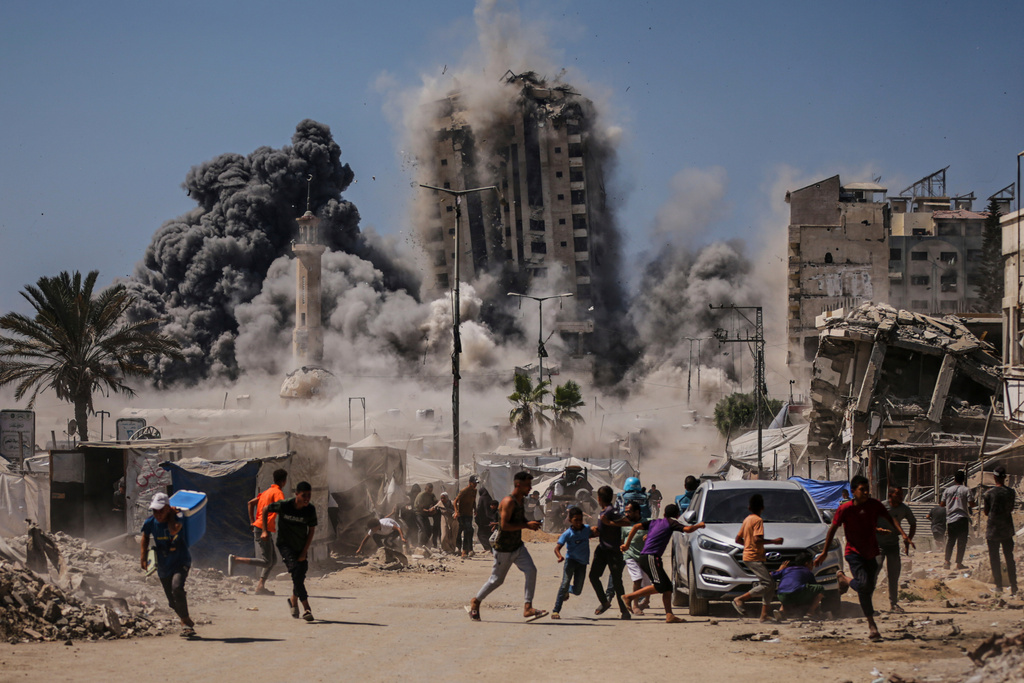 People run for cover during an Israeli airstrike on a high-rise building in Gaza City, Friday, Sept. 5, 2025, after the Israeli army issued a warning.
