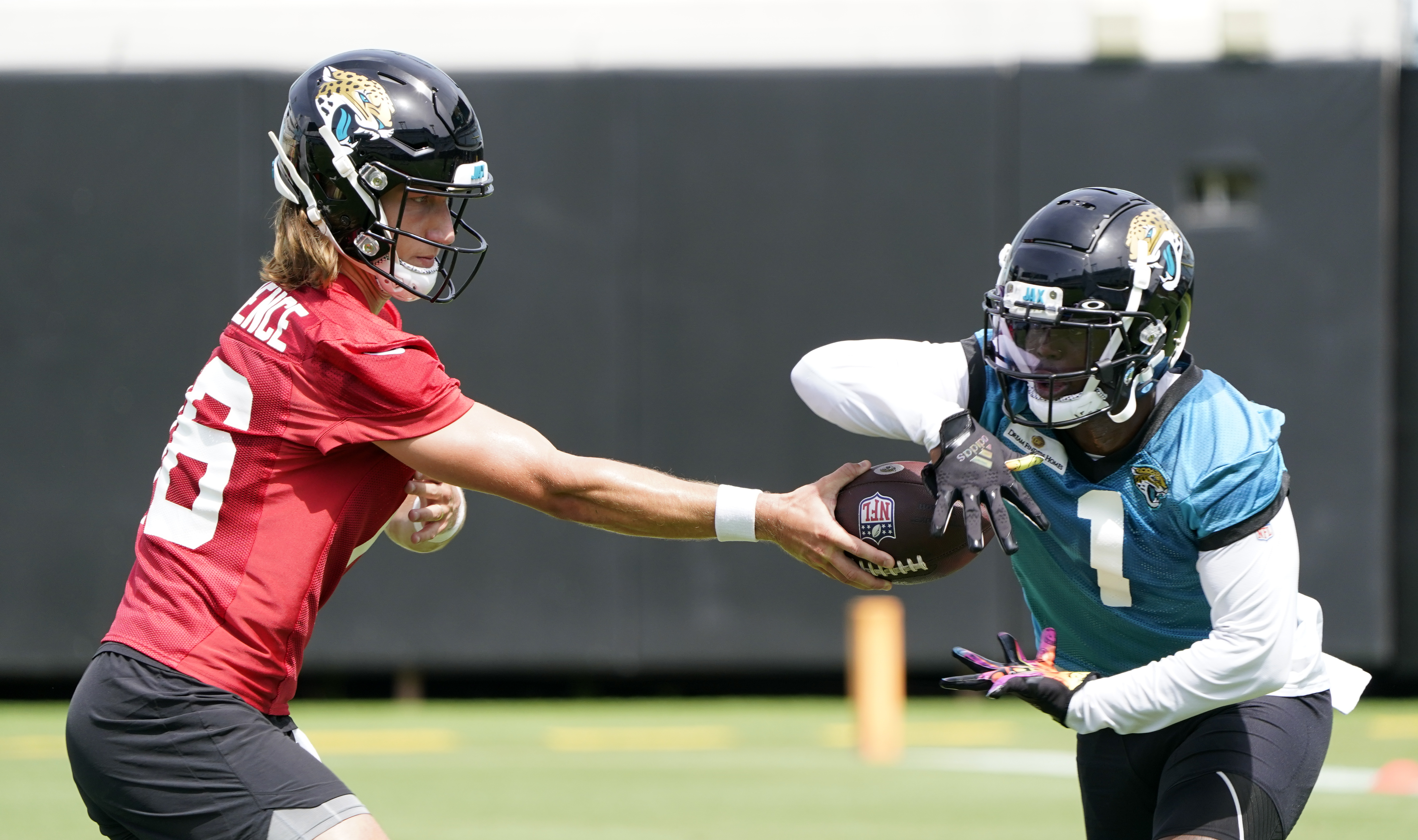 Jacksonville Jaguars QB Trevor Lawrence hands ball to running back Travis Etienne during practice, May 23, 2022