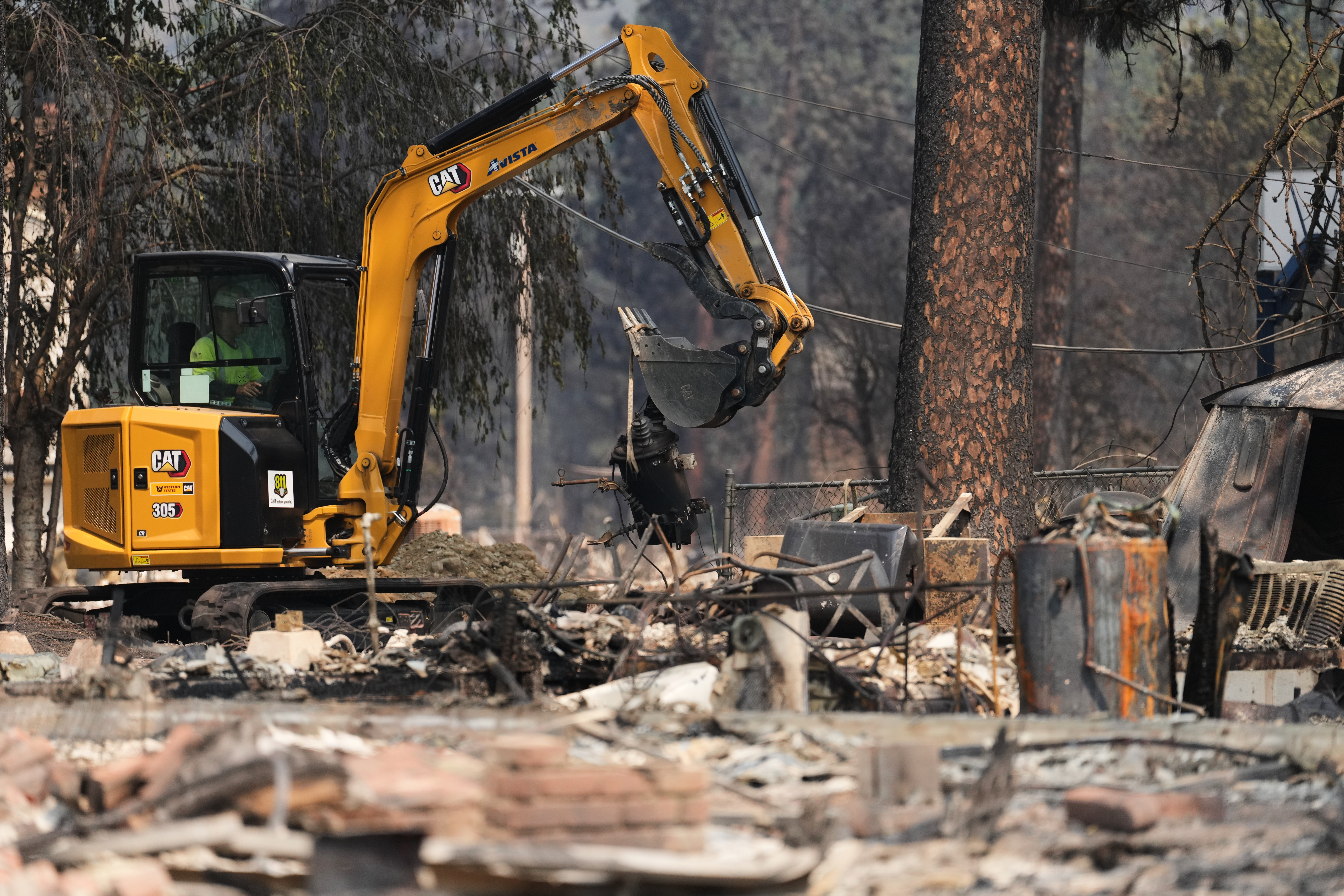 Crews work near several burned down houses after a wildfire hit the northwest part of Spokane, Wash., Tuesday, Aug. 4, 2026.
