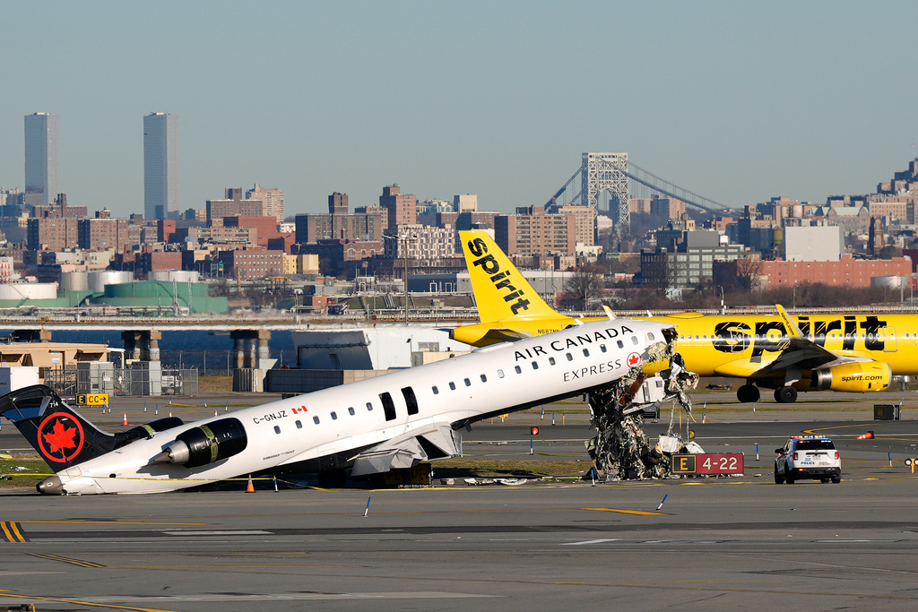 A Spirit Airlines jet taxis past an Air Canada Express jet sitting on the side of a runway, Tuesday, March 24, 2026, where it had collided with a Port Authority fire truck Sunday night at LaGuardia Airport in New York. 