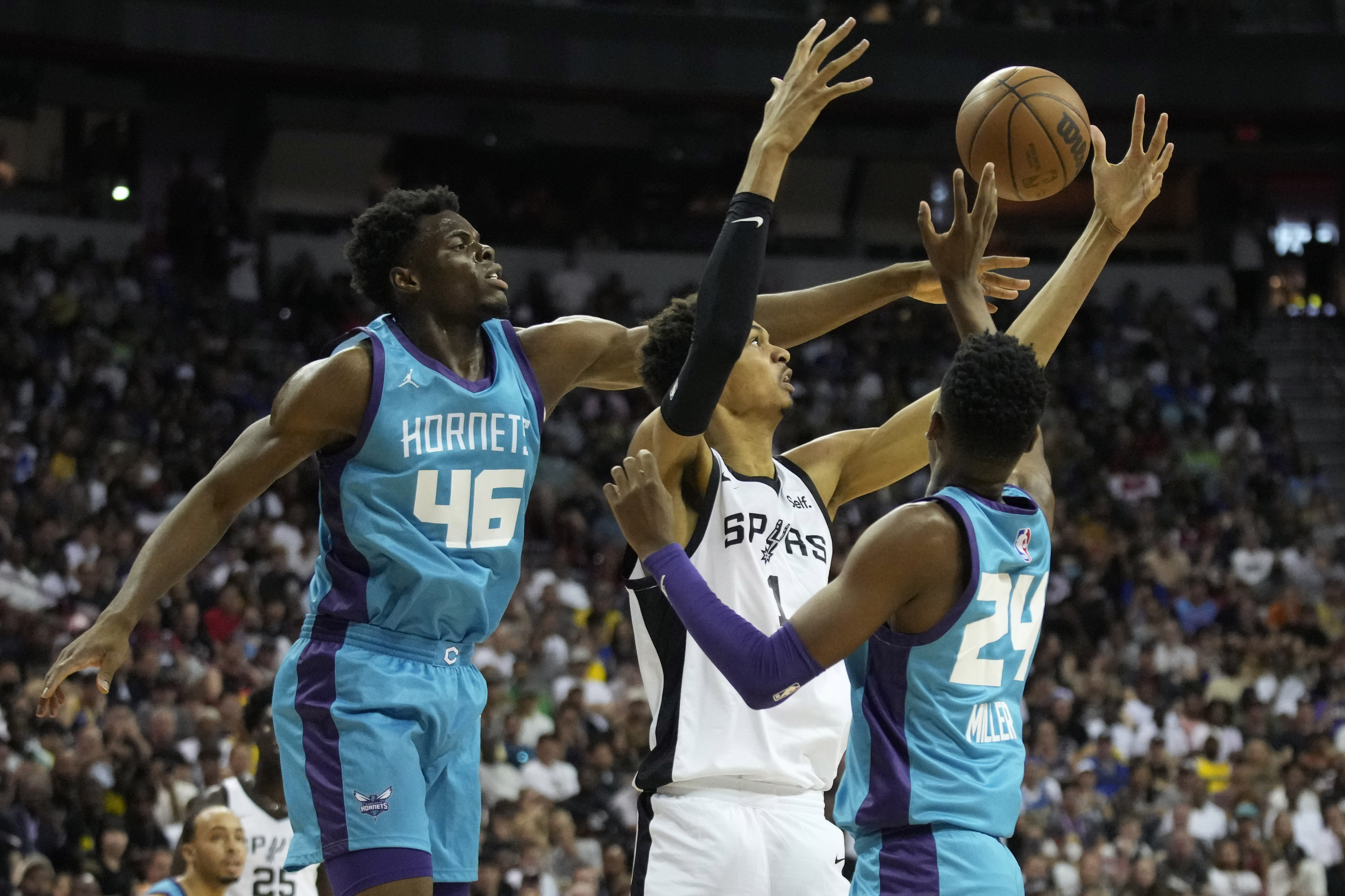 Charlotte Hornets' James Nnaji, left, and San Antonio Spurs' Victor Wembanyama battle for a rebound beside Charlotte Hornets' Brandon Miller, right, during the first half of an NBA summer league basketball game Friday, July 7, 2023, in Las Vegas. 