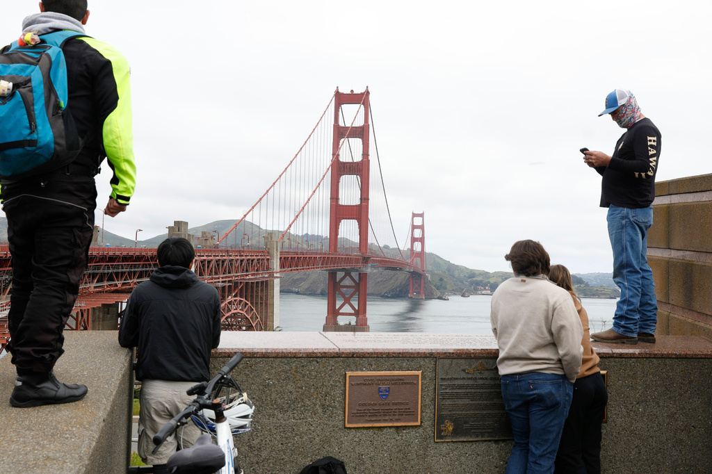 FILE - Pedestrians and bicyclists wait outside the pedestrian gate on the south side of the Golden Gate Bridge, which is closed due to protesters, April 15, 2024, in San Francisco.