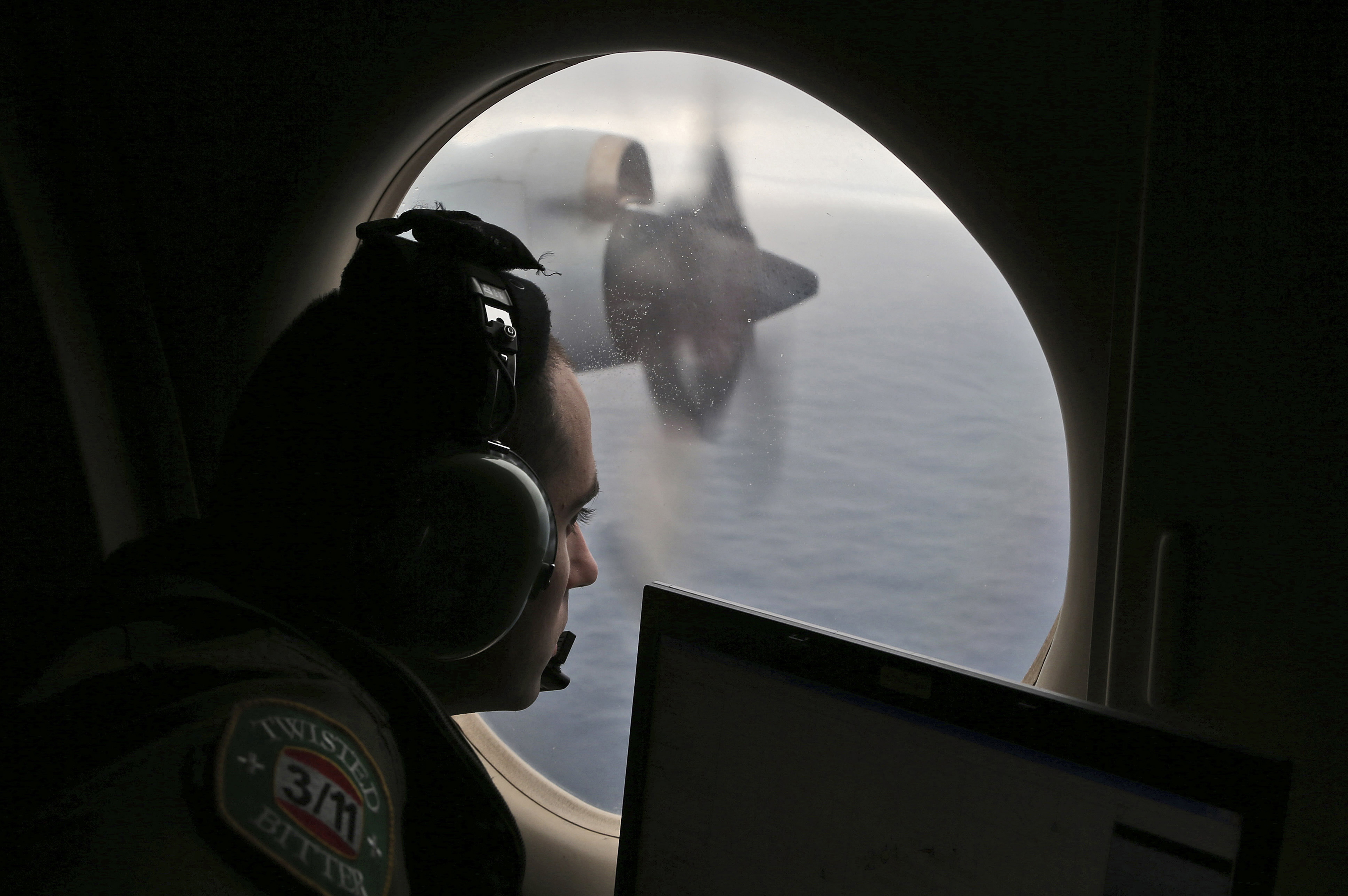 FILE - Flight officer Rayan Gharazeddine scans the water in the southern Indian Ocean off Australia from a Royal Australian Air Force AP-3C Orion during a search for the missing Malaysia Airlines Flight MH370, March 22, 2014. 