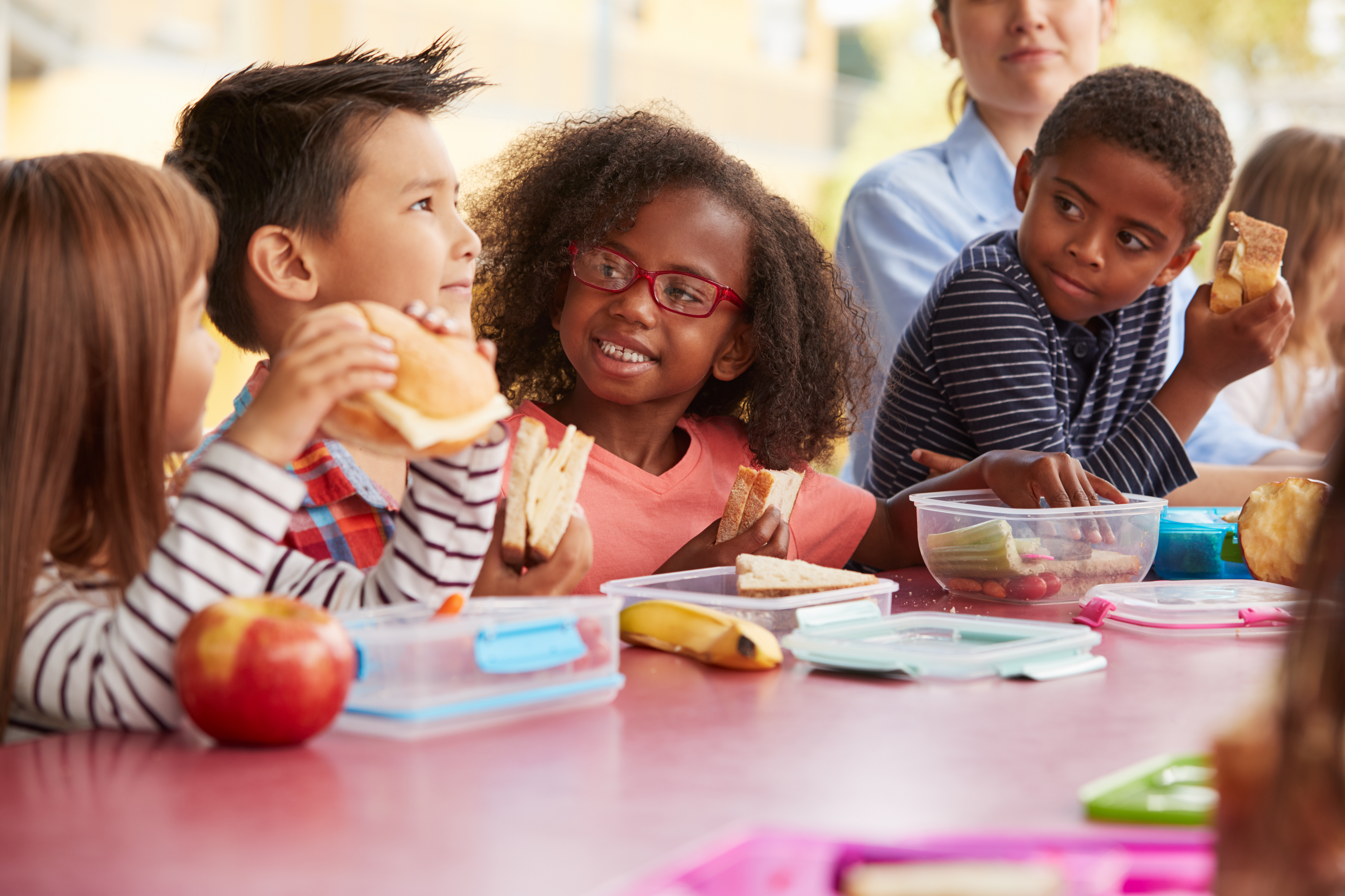 School-age kids eating lunch at a table together.