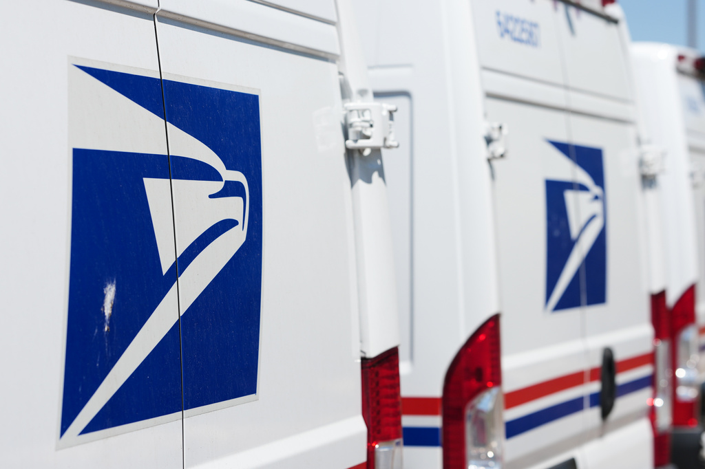Delivery vans bearing the logo sit during a protest staged as part of a countrywide National Day of Action Tuesday, July 28, 2026, outside the main United States Postal Service headquarters in northeast Denver.
