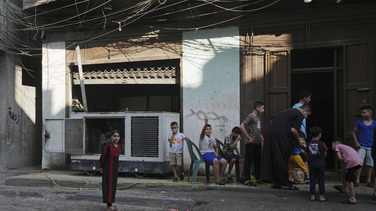 Children hang out near an electricity generator under electricity distribution wires