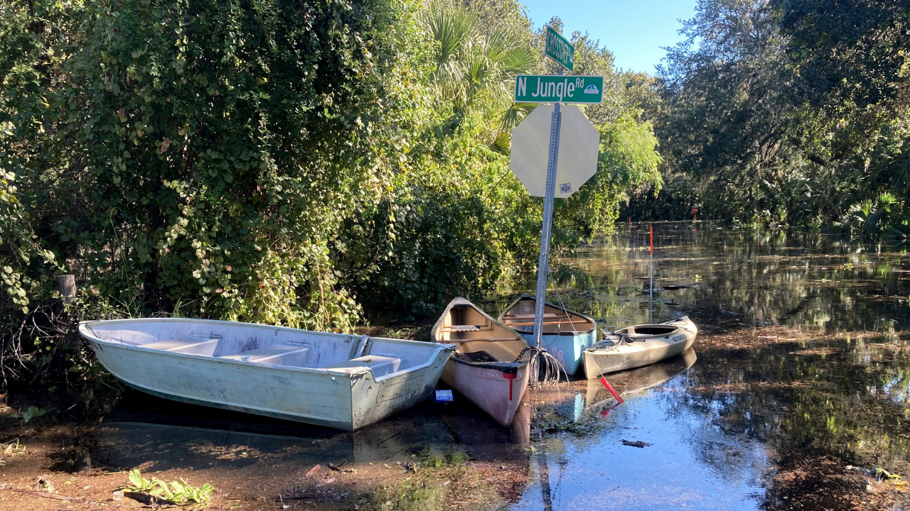Canoes and kayaks sit tied up to a sign on a flooded street in Seminole County, Fla.